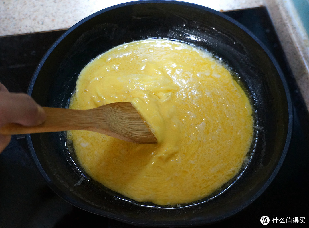 6.等到底部蛋液开始凝结的时候，拿起木铲，用推的手法把底部熟的蛋液推起，让上层生的蛋液流下去填补空白。