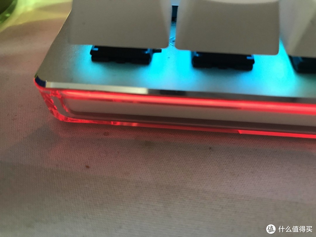 键盘面是铝合金材质，边缘有类似iPhone5那种切边，底部透明的亚力克就是为了整个灯带，大写锁定的时候为红色，win键锁定则是蓝色，两个一起锁定就变成紫色。键盘在使用中就不亮灯，闲置状态下就会7彩变换，真的很RGB！！！