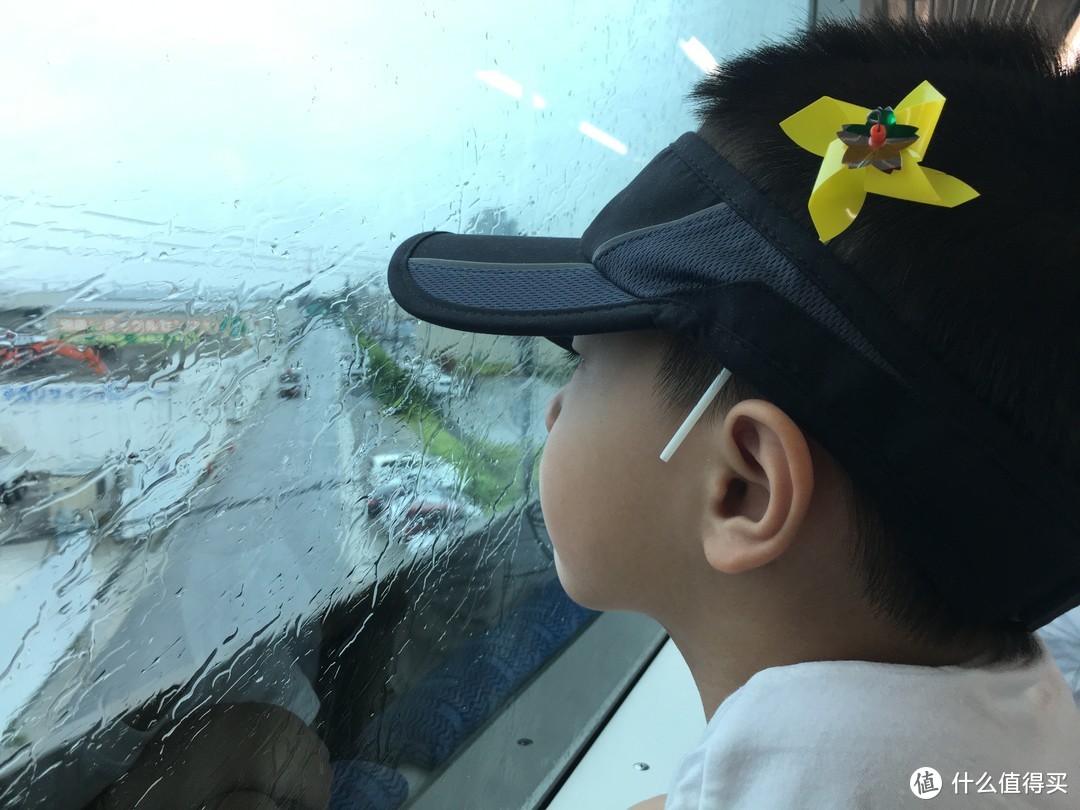 依旧下着雨，小宝有点忧伤的看着车窗外，帽子上别着的小风车，是前一晚酒店送给小朋友的礼物。