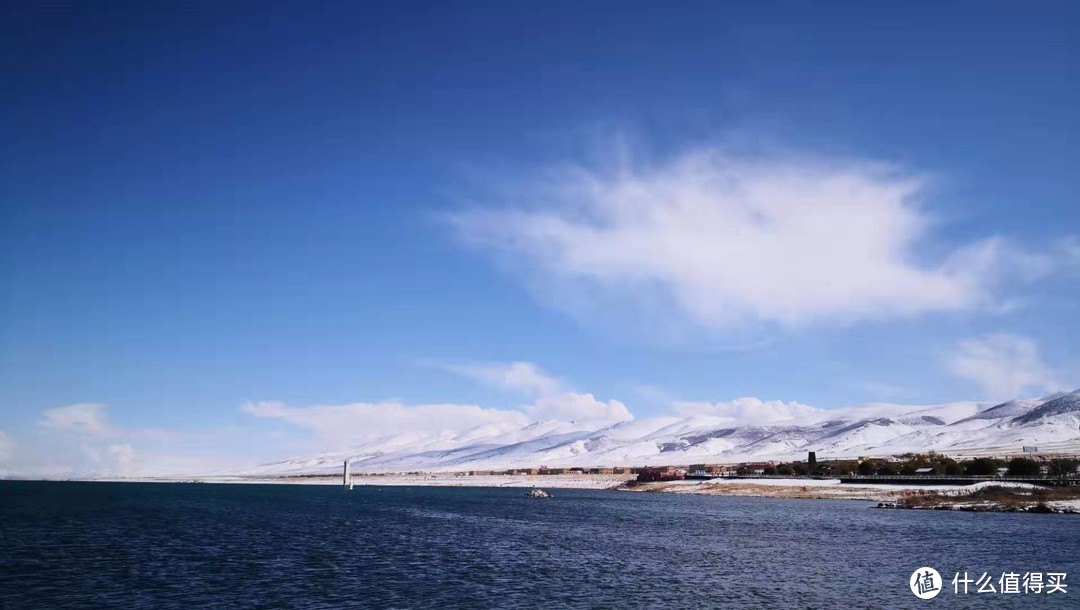 刚下过雪天空放晴，湛蓝的湖水映衬蓝色白云和远方的雪上，美