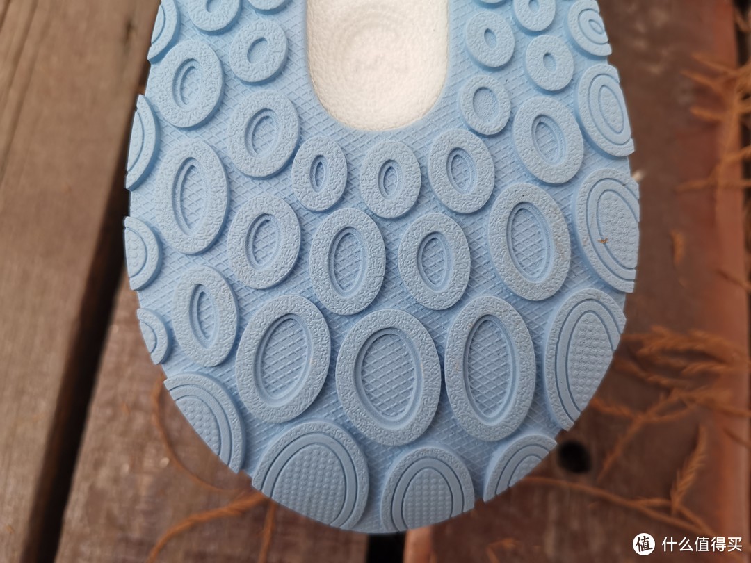 鞋后跟部位，可以在上图中看到，整个跑鞋的大底采用了一整块的浅蓝色橡胶大底，在纹路设计上采用的是椭圆形凹槽和浮点设计，用于增加跑鞋的抓地性。