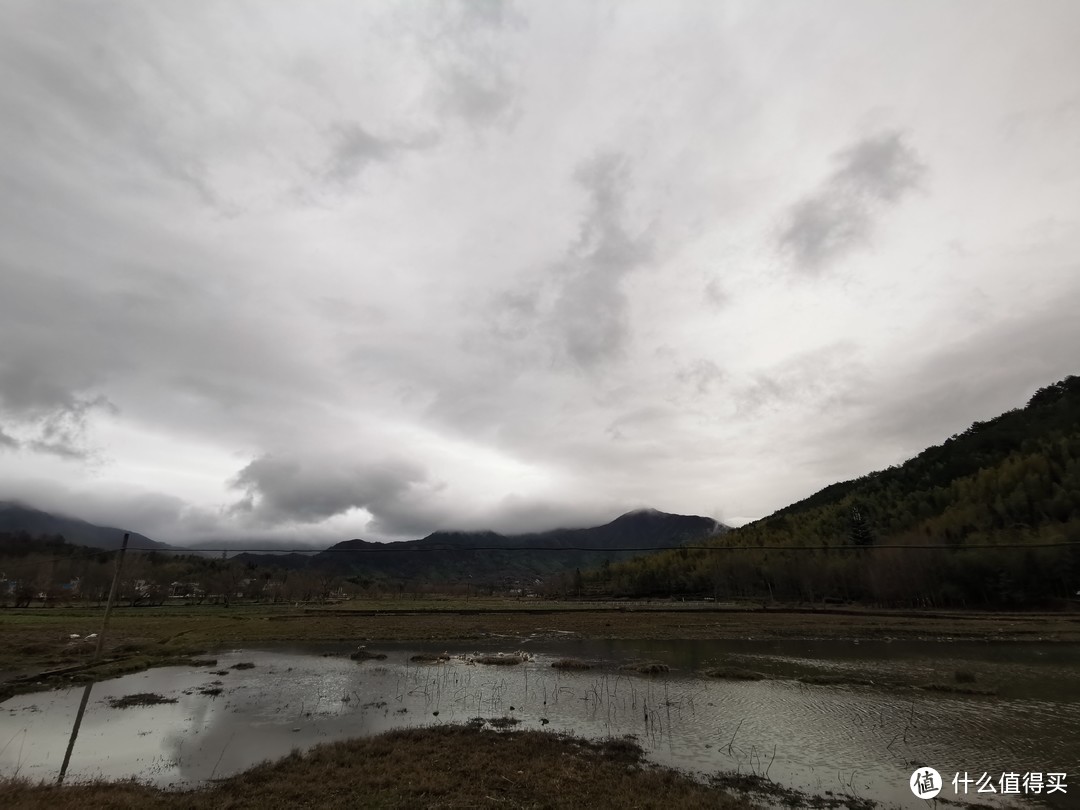 酒店去宏村的路上，一个池塘，远处黄山山脉，以及慢慢放晴的天空