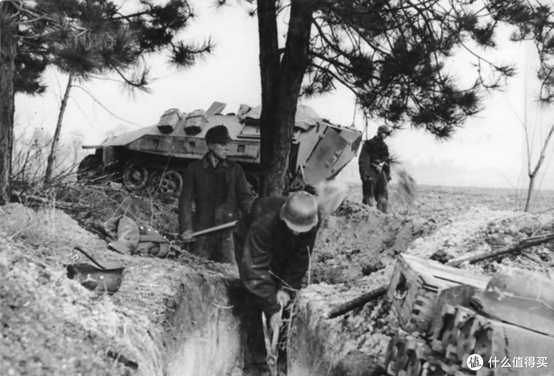 正在挖掘战壕的德军士兵与人民冲锋队队员，背景处为一辆Sd.kfz. 251装甲车。1945年，德国境内