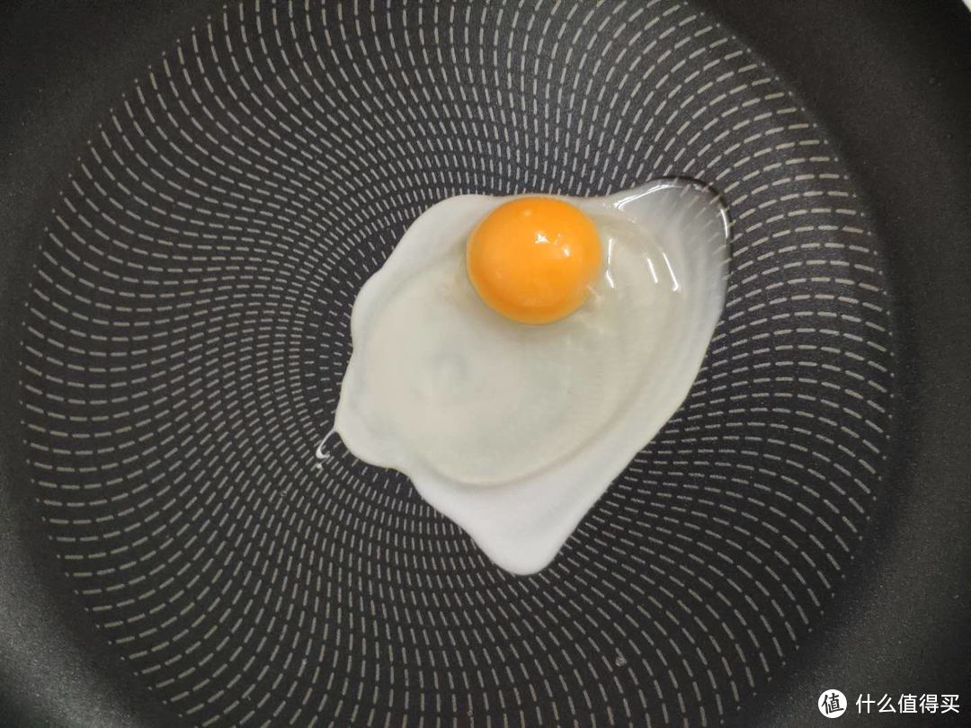 中间敲入一个鸡蛋，蛋黄稍稍往低处滑去