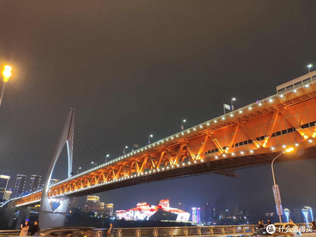 夜晚的嘉陵江大桥亮起了灯光，江两岸的建筑也亮起来灯光，整个城市灯火通明，真不愧是国际大都市，俺们村这时候出门都得带手电筒