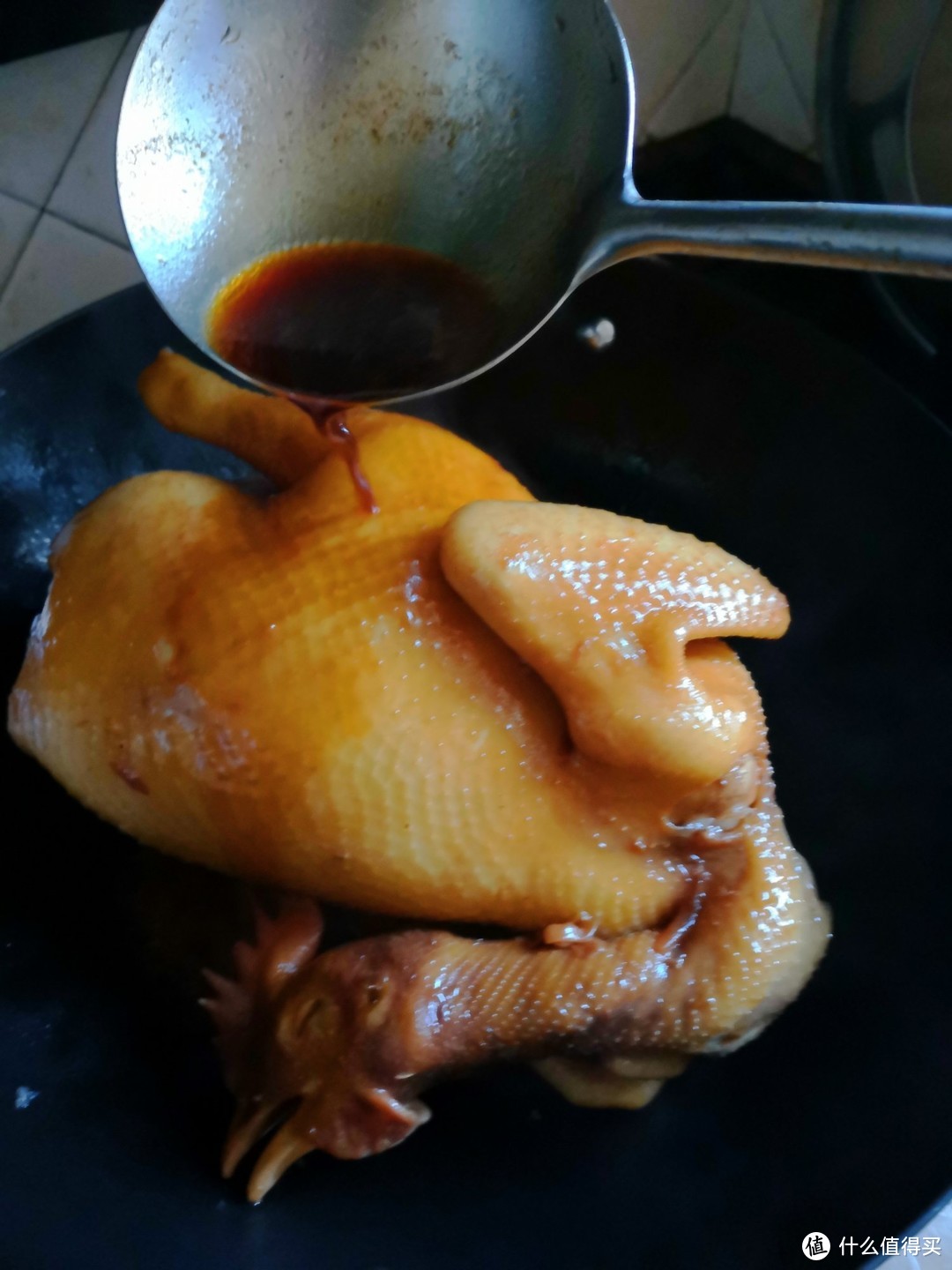 用炒勺把酱油淋在鸡身上，加入一碗清水，再加入一块红片糖，最后放一个小葱结进去，煮开后，没隔网，用鸡脚垫锅底，把鸡身挂起，防止鸡皮粘锅，盖上锅盖小火焖十分钟。