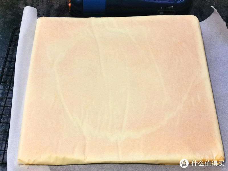 烤架上铺上一层油纸，把烤好的蛋糕取出，立即倒扣在烤架上，晾至温热时将油纸撕下；