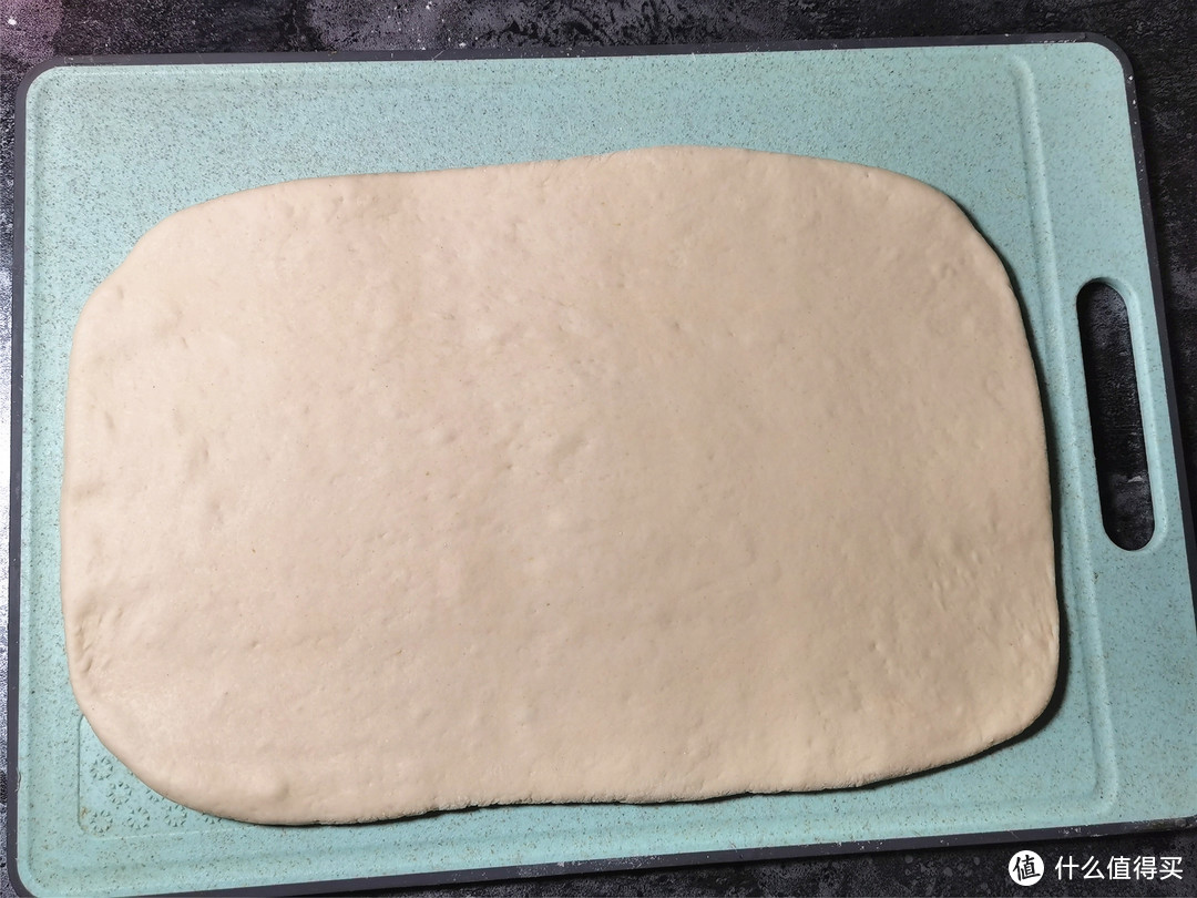 面团取出，放案板上撒上干粉揉匀，用擀面杖擀成厚度约1厘米的长方形面皮；