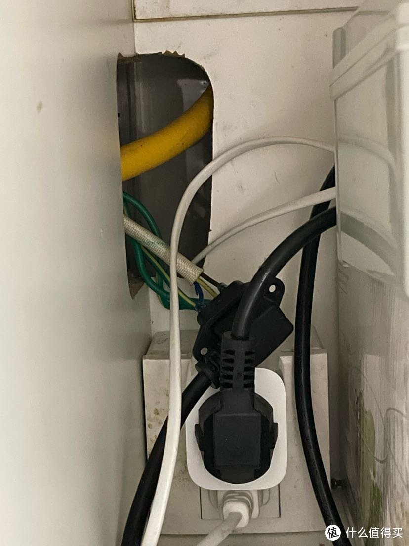 烟机电源插头和转接排插从橱柜缝隙拉进橱柜，接入米家智能插座（白色物体）
