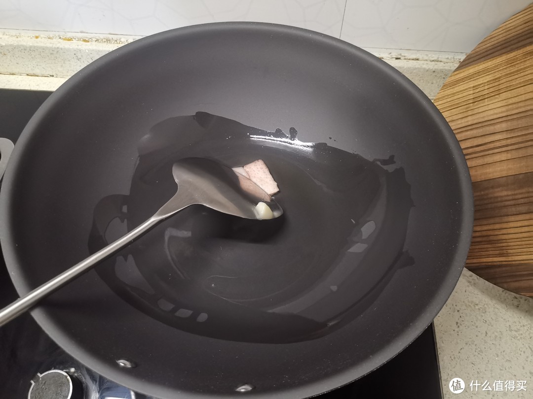 把锅刷干净之后就要开始养锅，用了一块肥猪肉，开小火使之出油，均匀的覆盖整个锅体