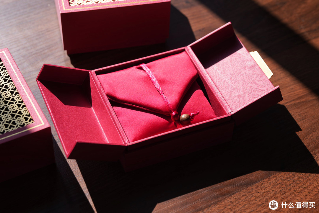 去掉顶盖后，盒子可以对半翻开，里面是一个红色绸缎材质的袋子
