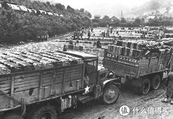 木质货斗的两吨半卡车从补给站运送汽油。此时的盟军运输体系是物资由先遣后勤部队将物资由诺曼底滩头运送至各前线补给站，各师的运输连再将物资由补给站运送至各部队。